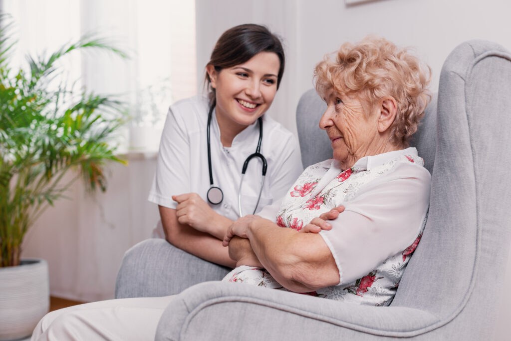 A nurse talking with an older woman seated comfortably at home